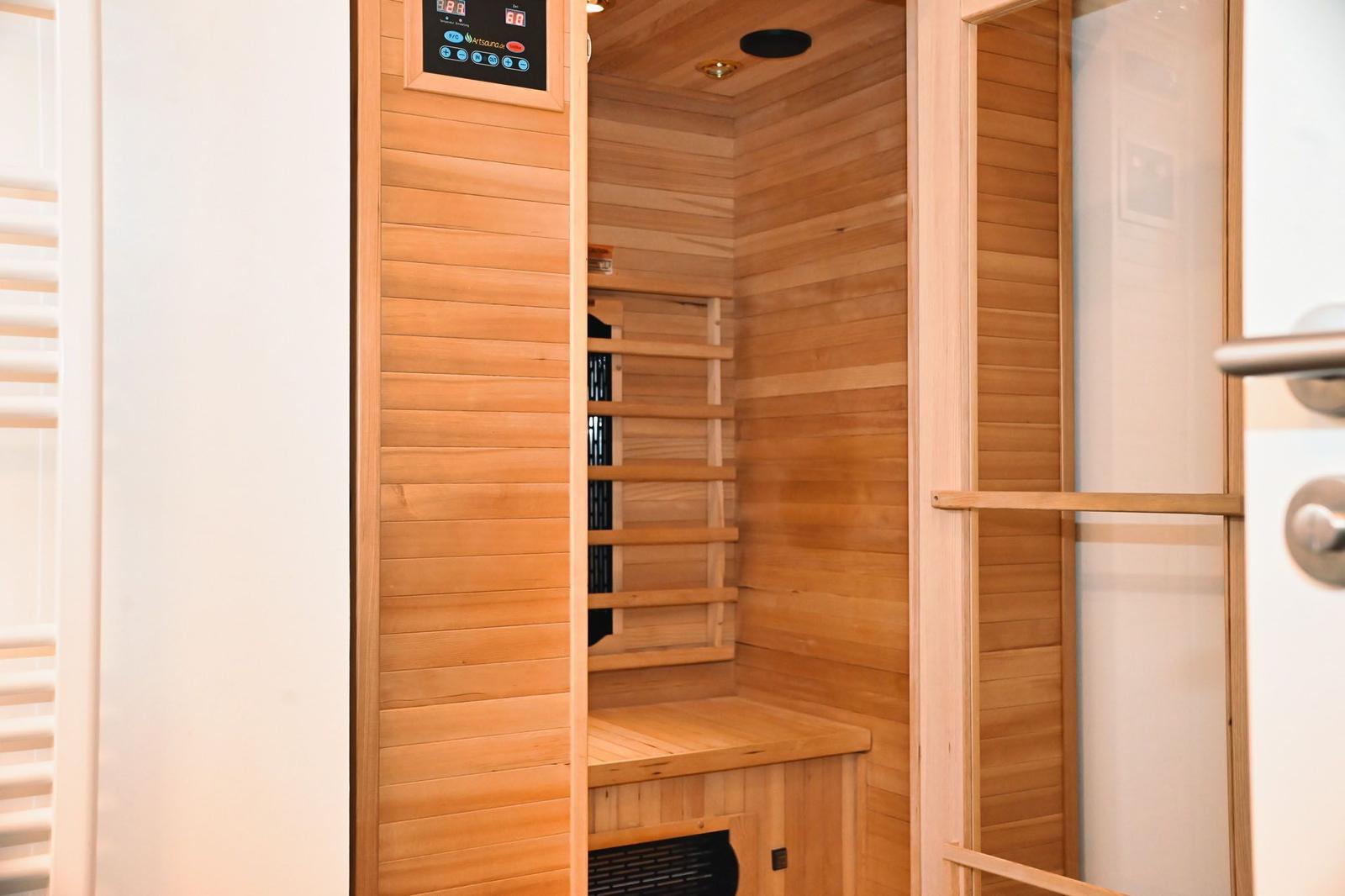 Innere Ansicht einer Holzsauna mit Sitzbank und Steuerungselementen an der Wand.