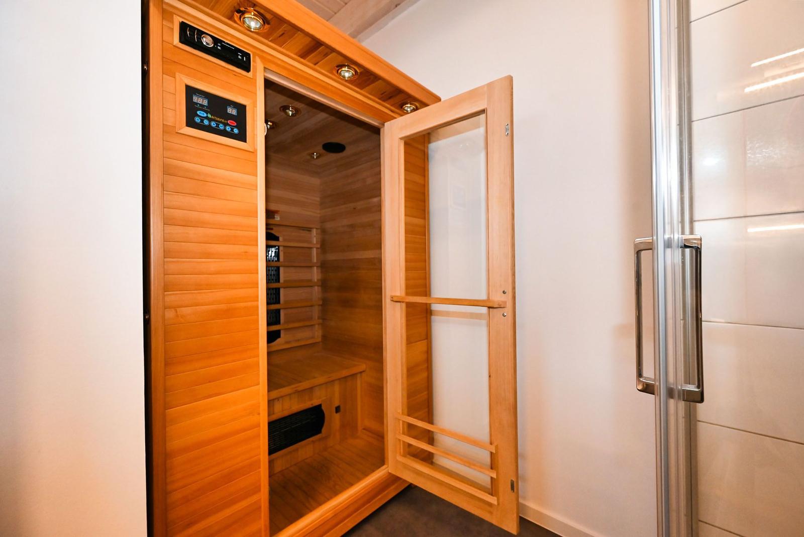 Eine Holzsauna mit geöffneter Tür und Bedienfeld an der Wand.