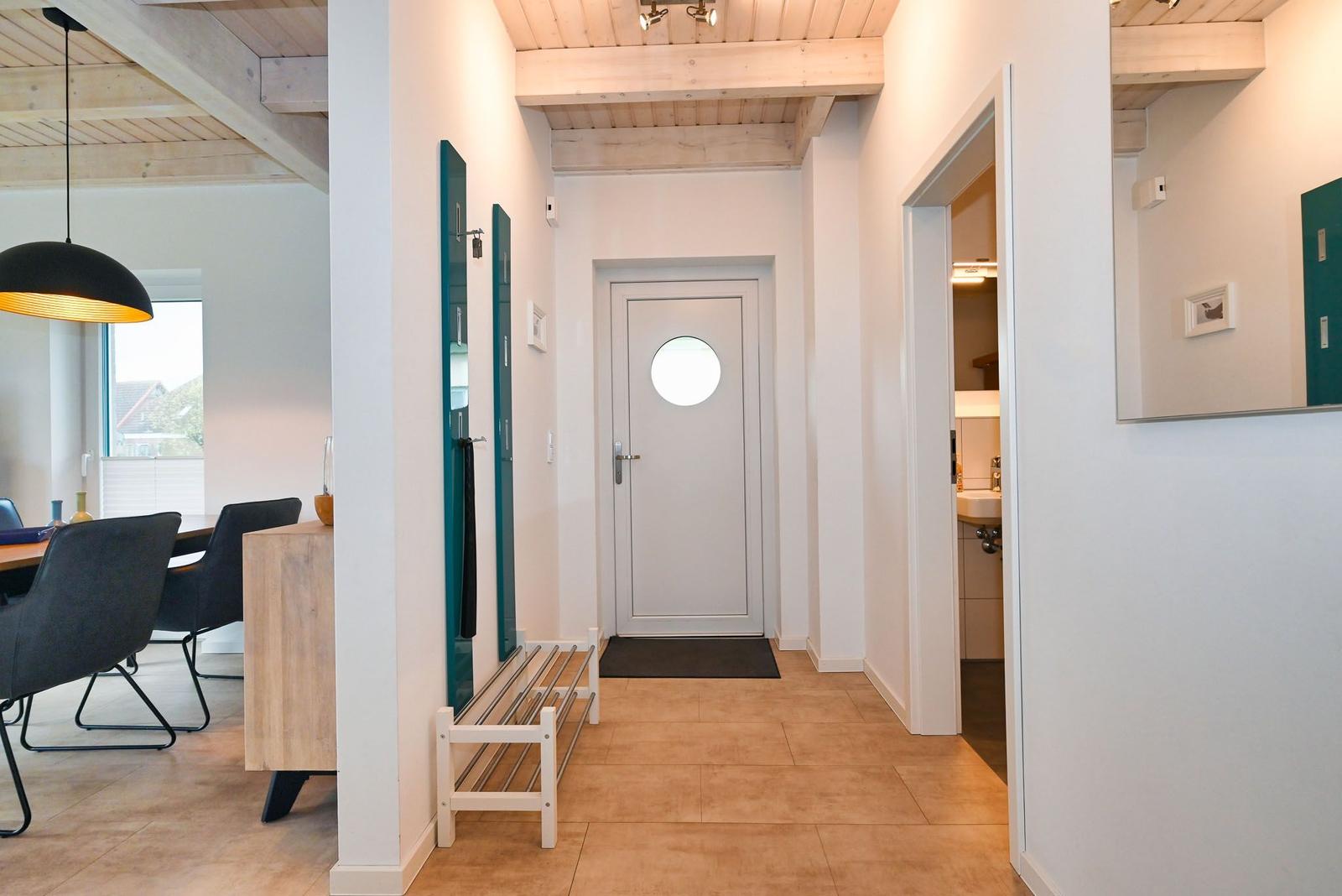 Hausgang mit Tür, Bad und Essbereich mit Tisch und Stühlen.