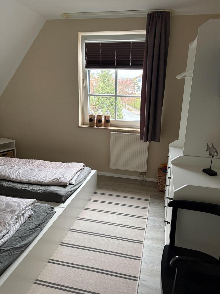 Zimmer mit Doppelbett, Schreibtisch und Fenster mit Blick nach draußen.