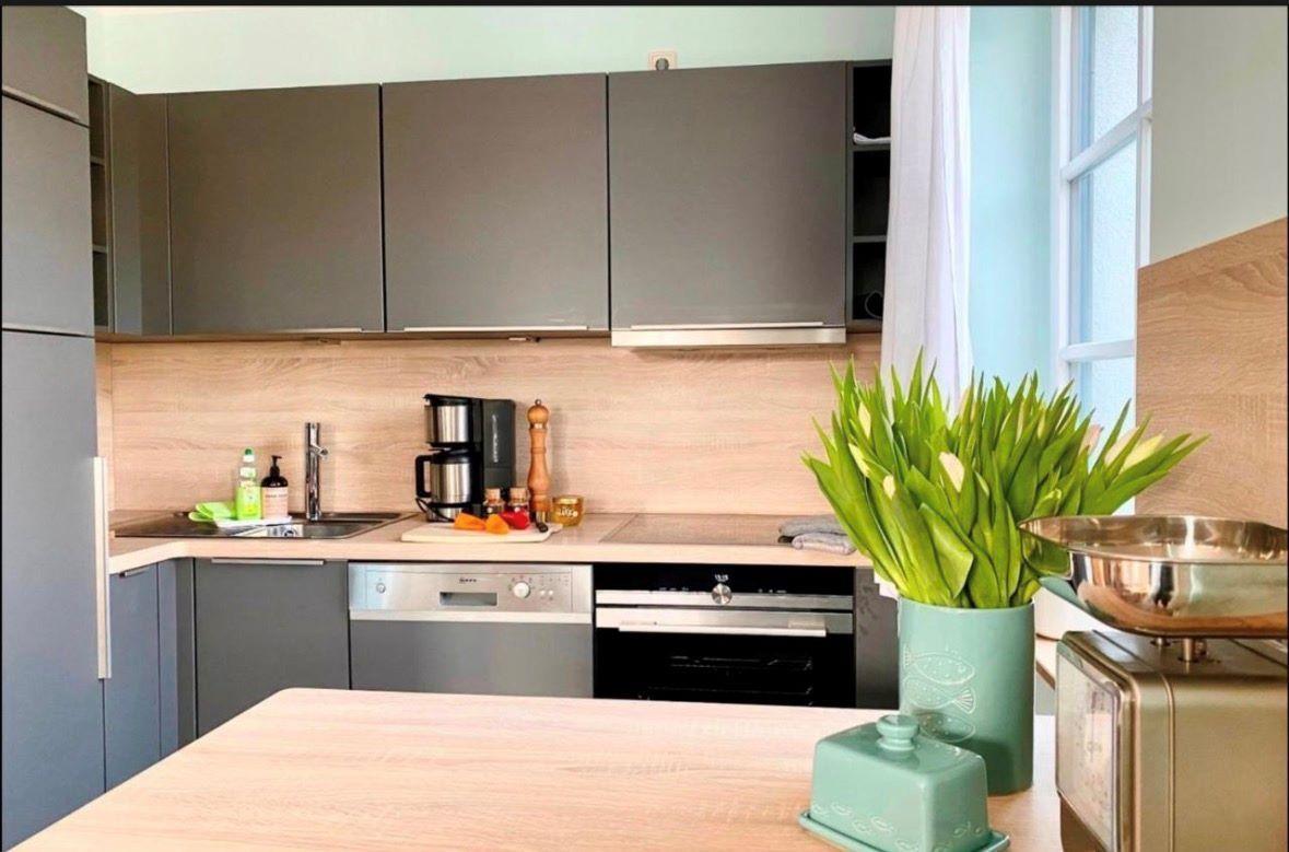 Moderne Küche mit grauen Schränken, Holzoberflächen und Küchenzeile mit Fenster.
