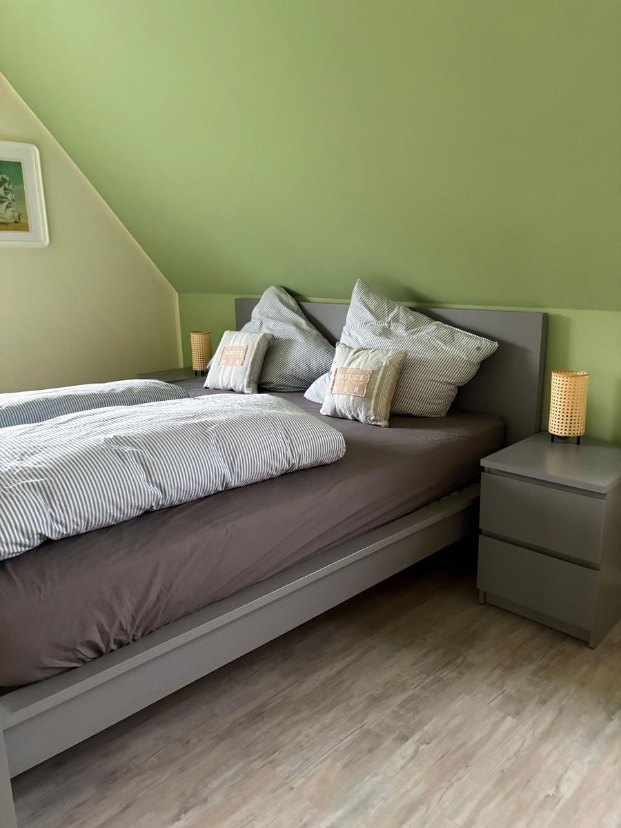 Schlafzimmer mit Bett, Nachttisch und grüner Wand