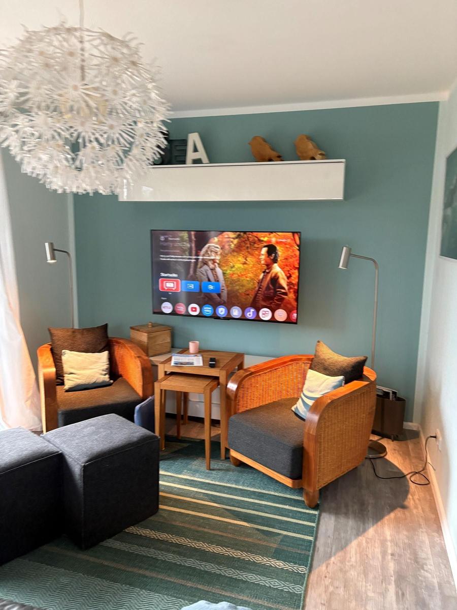 Wohnzimmer mit zwei Sesseln, Fernseher und Deckenleuchte.