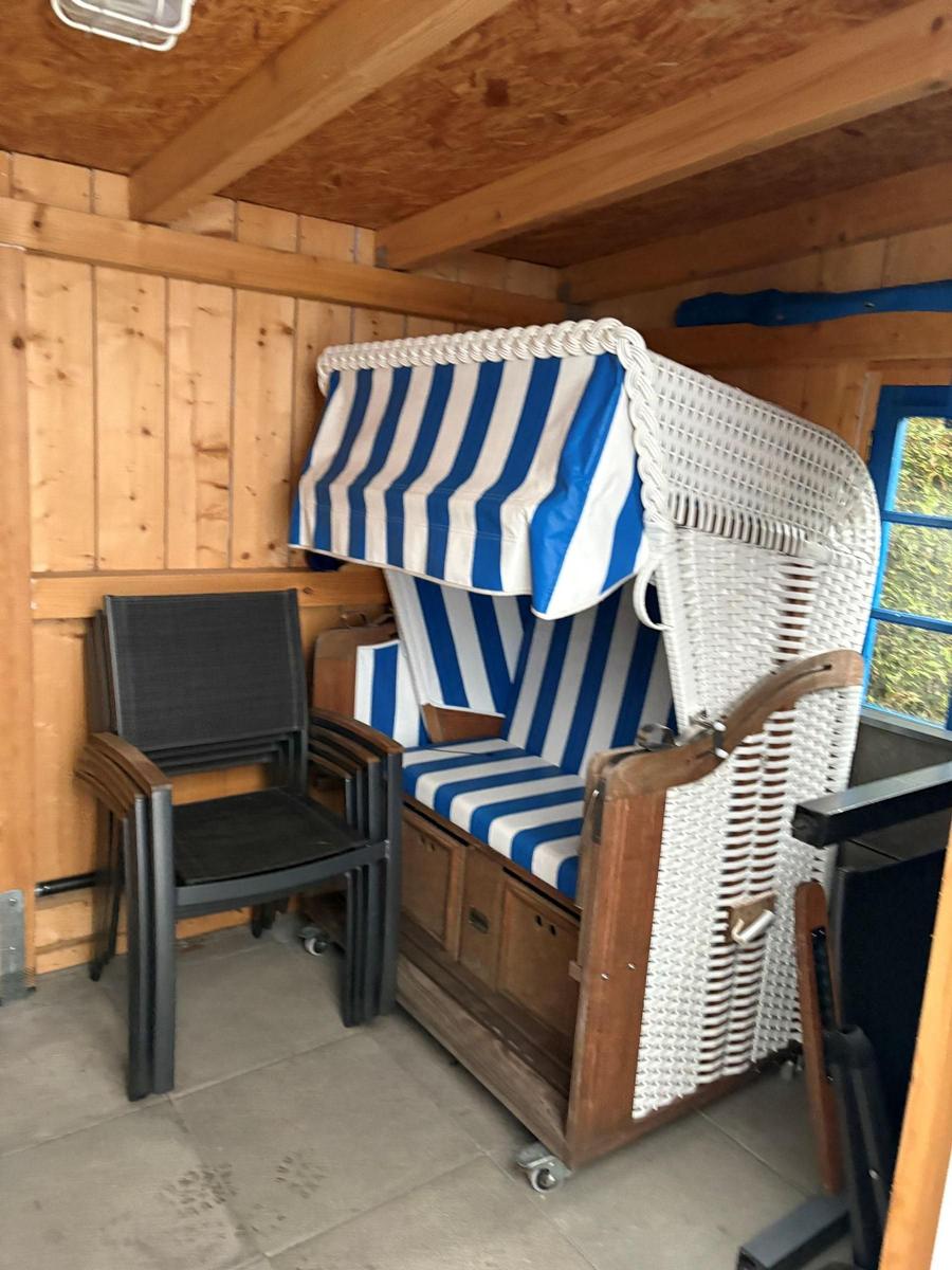 Hochwertige Strandkörbe mit blau-weißem Stoff in Holzhaus. Neben einem Stuhl.