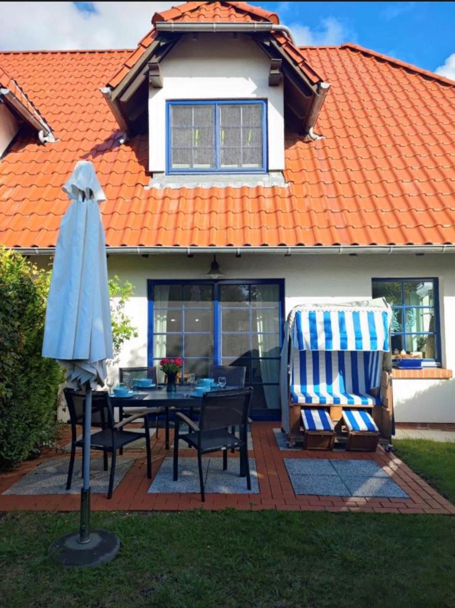 Terrasse mit Tisch, Stühlen und Strandkörben unter blau-weißem Zelt.