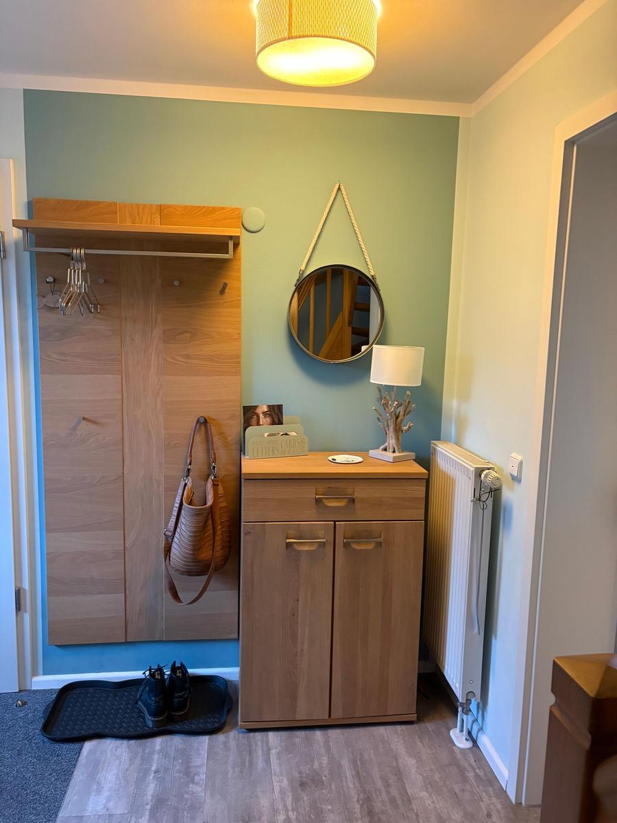 Eingangsbereich mit Kleiderschrank, Spiegel und Schrank. Holzmöbel und warmes Licht.