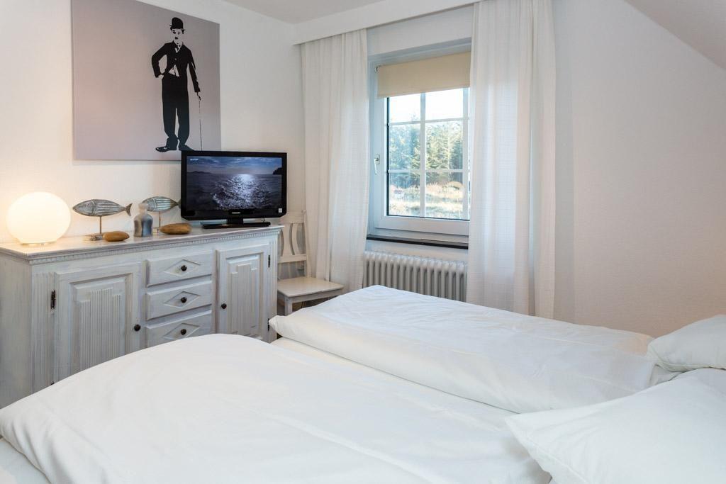 Schlafzimmer mit Doppelbett, Fenster, TV und Schrank.