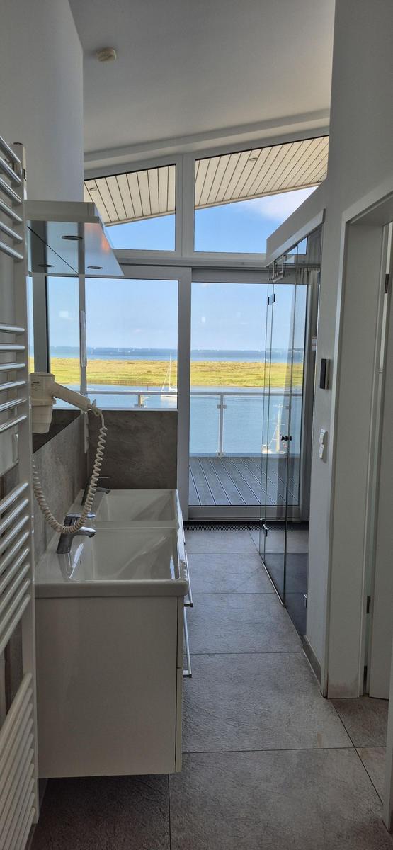 Badezimmer mit Dusche und Blick auf Wasser und Strand