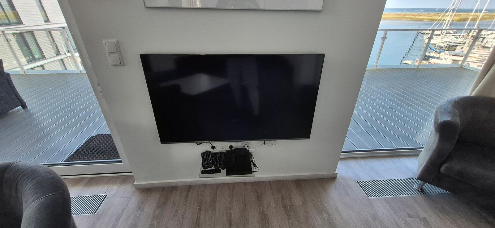 TV an der Wand, Blick auf den Hafen mit Booten.