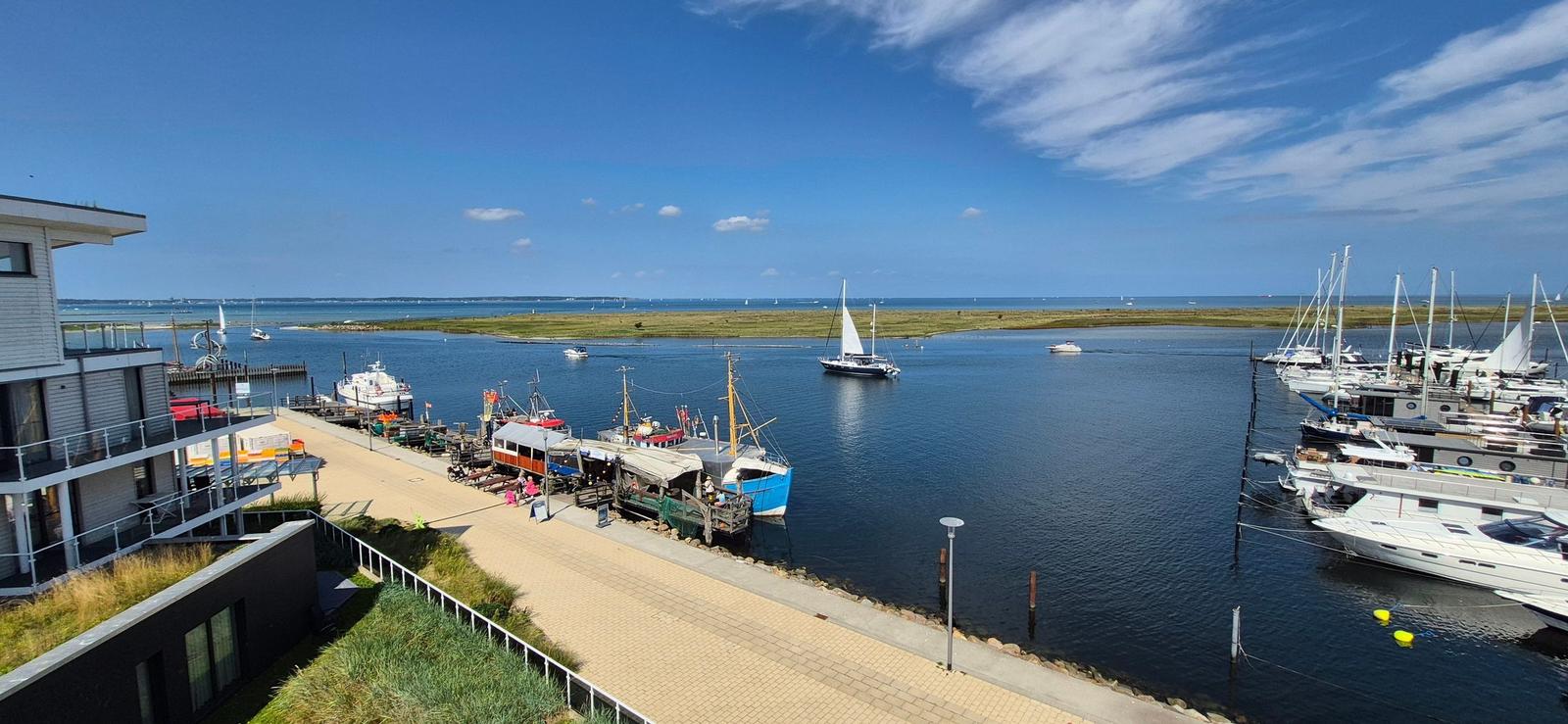 Hafen mit Booten und Blick auf die Insel unter blauem Himmel.