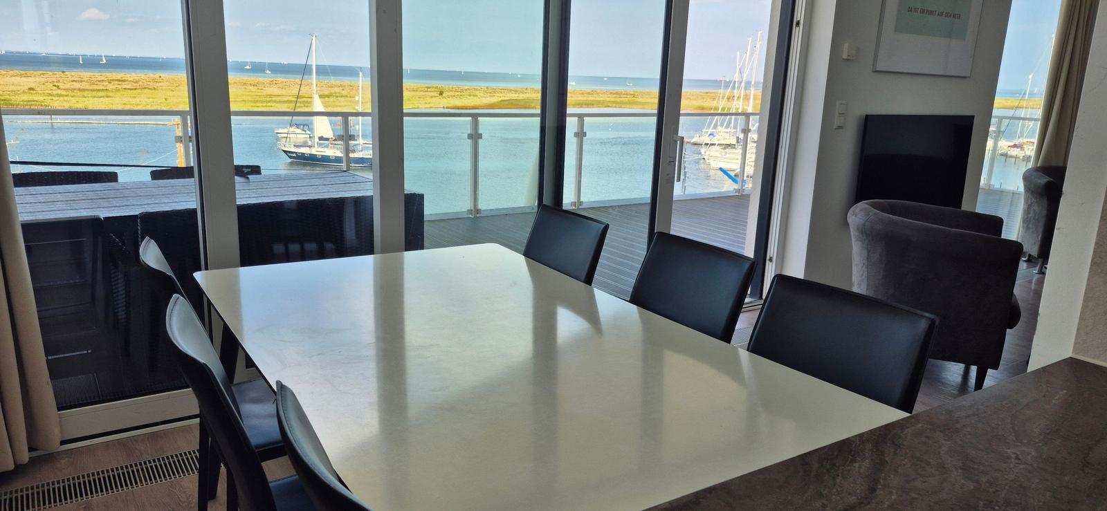 Esszimmer mit Blick auf Hafen und Meer. Tisch, Stühle und Terrasse.