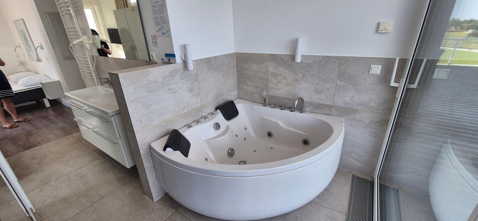 Bad mit Whirlpool, Waschbecken und Blick auf Balkon.