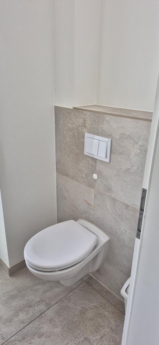 WC mit Wandmontage und Steuertaste an Steinwand