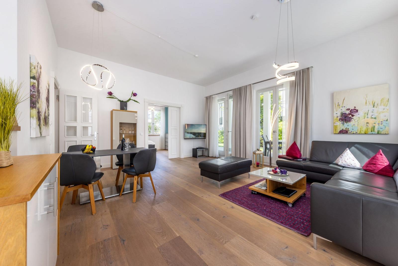 Wohn- und Essbereich mit Holzboden, Sofa, Esstisch und TV.