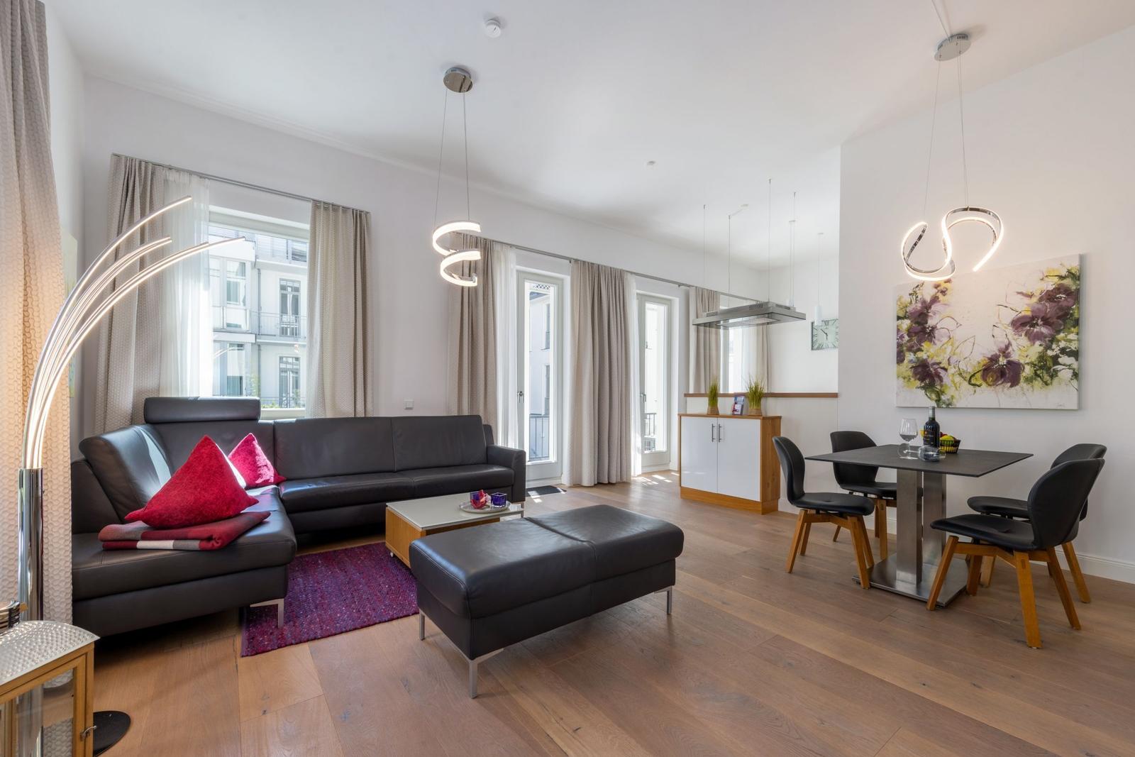 Wohn- und Essbereich mit Sofa, Esstisch und Fenstern.