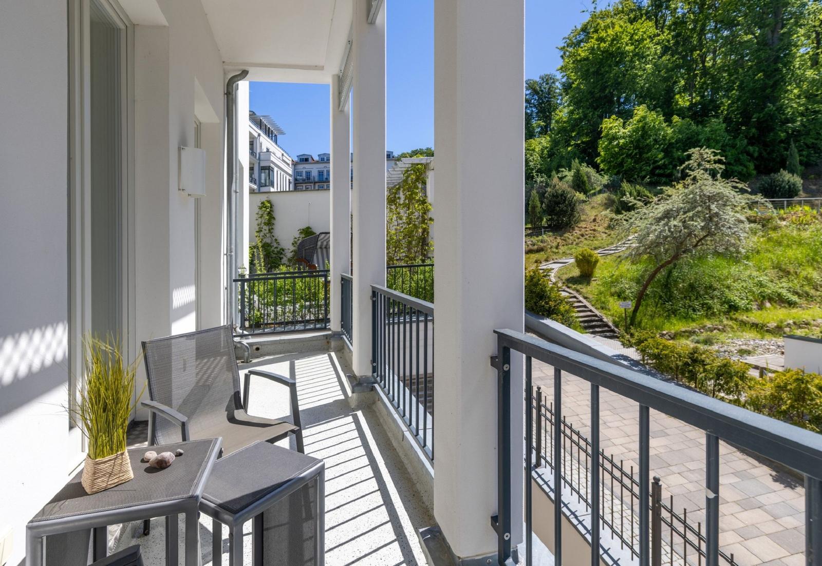 Terrasse mit Sitzgruppe und Blick auf grünen Hang.