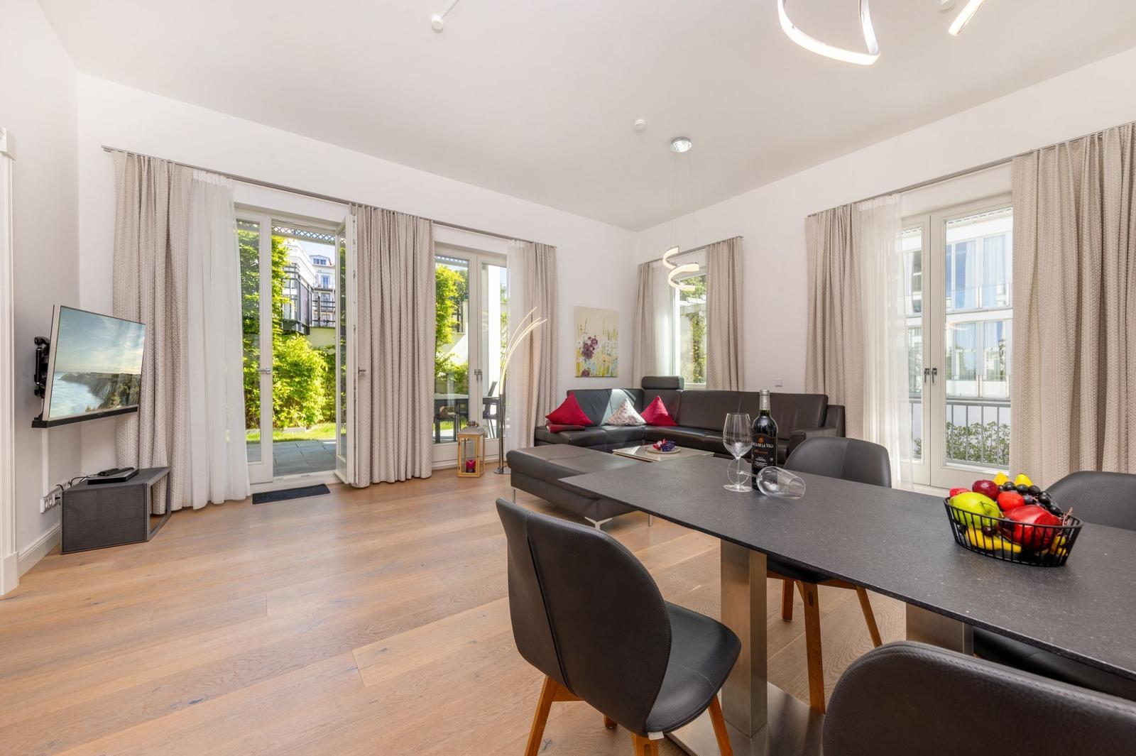 Wohn- und Essbereich mit Esszimmertisch, Sofa und TV. Durchgänge zu Terrasse und Balkon.