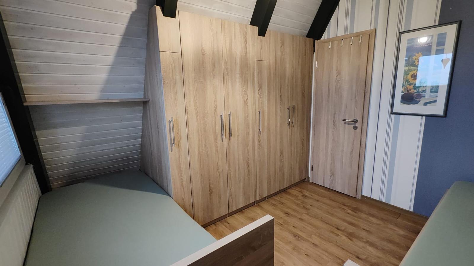 Schlafzimmer mit Holzschrank, Tür und Wandbild