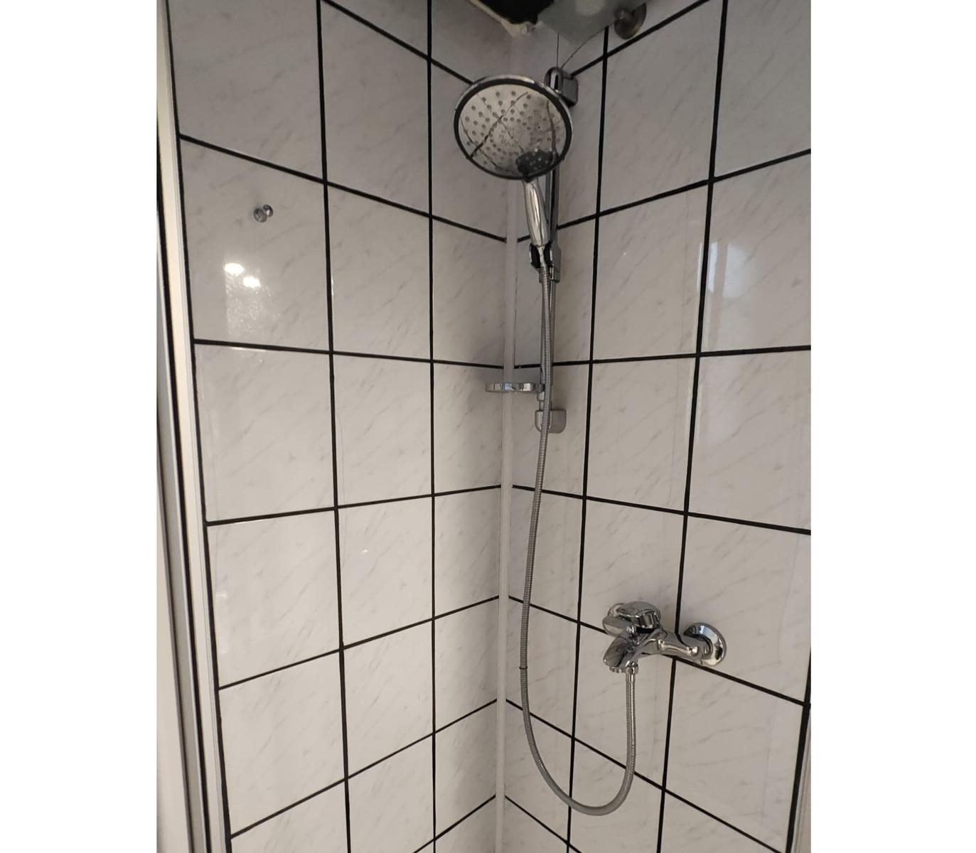 Dusche mit Chromarmatur und Duschbrause an Wand