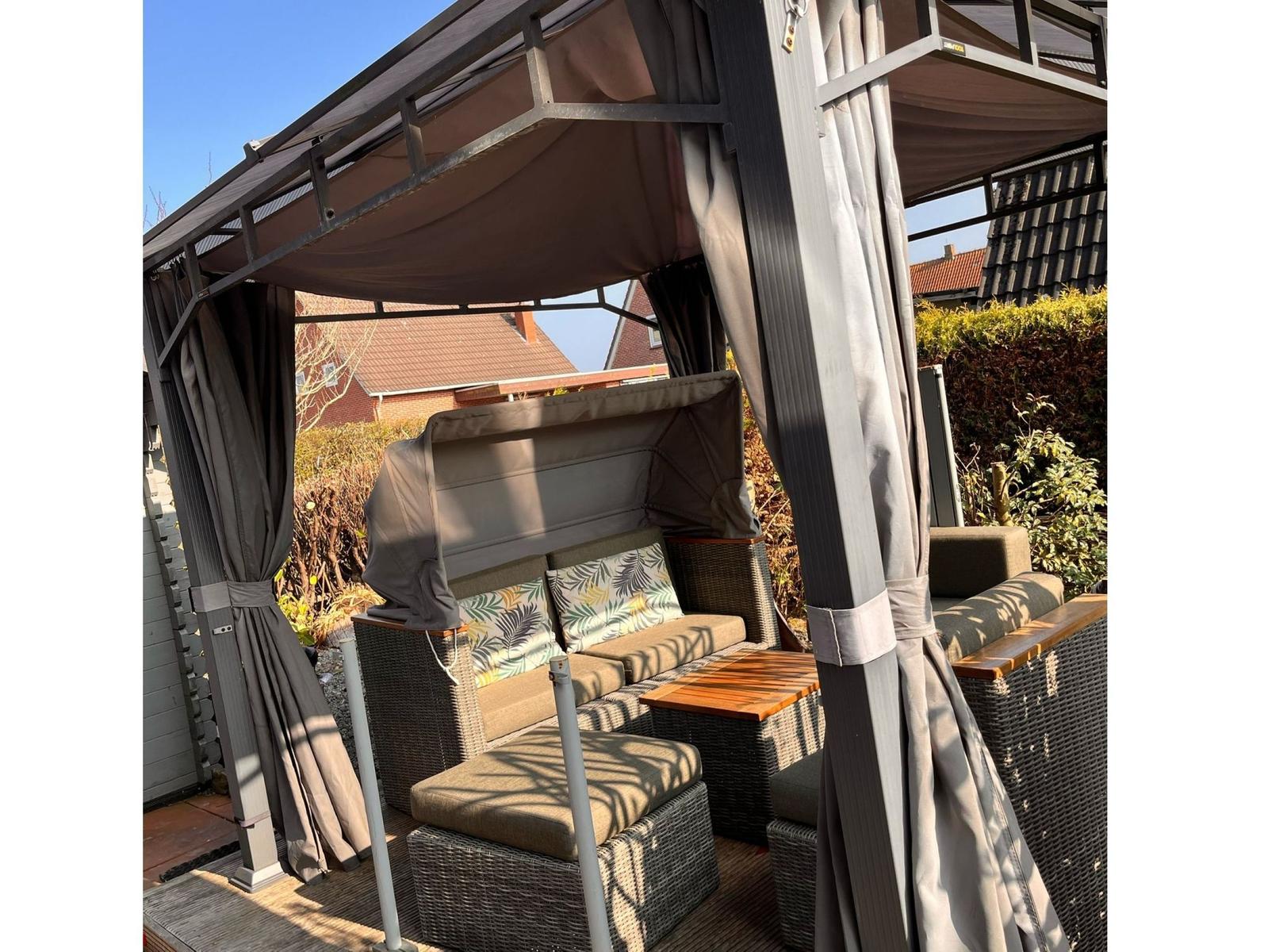 Terrasse mit Pavillon, Sitzgruppe und Tisch unter Schutz vor Sonne und Wind.