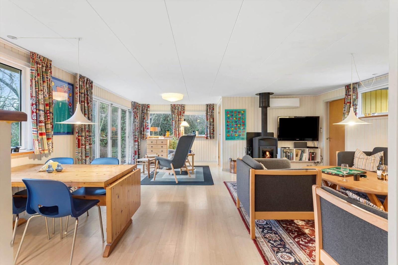 Living and dining area with wooden floor, sofa, dining table, and wood stove.