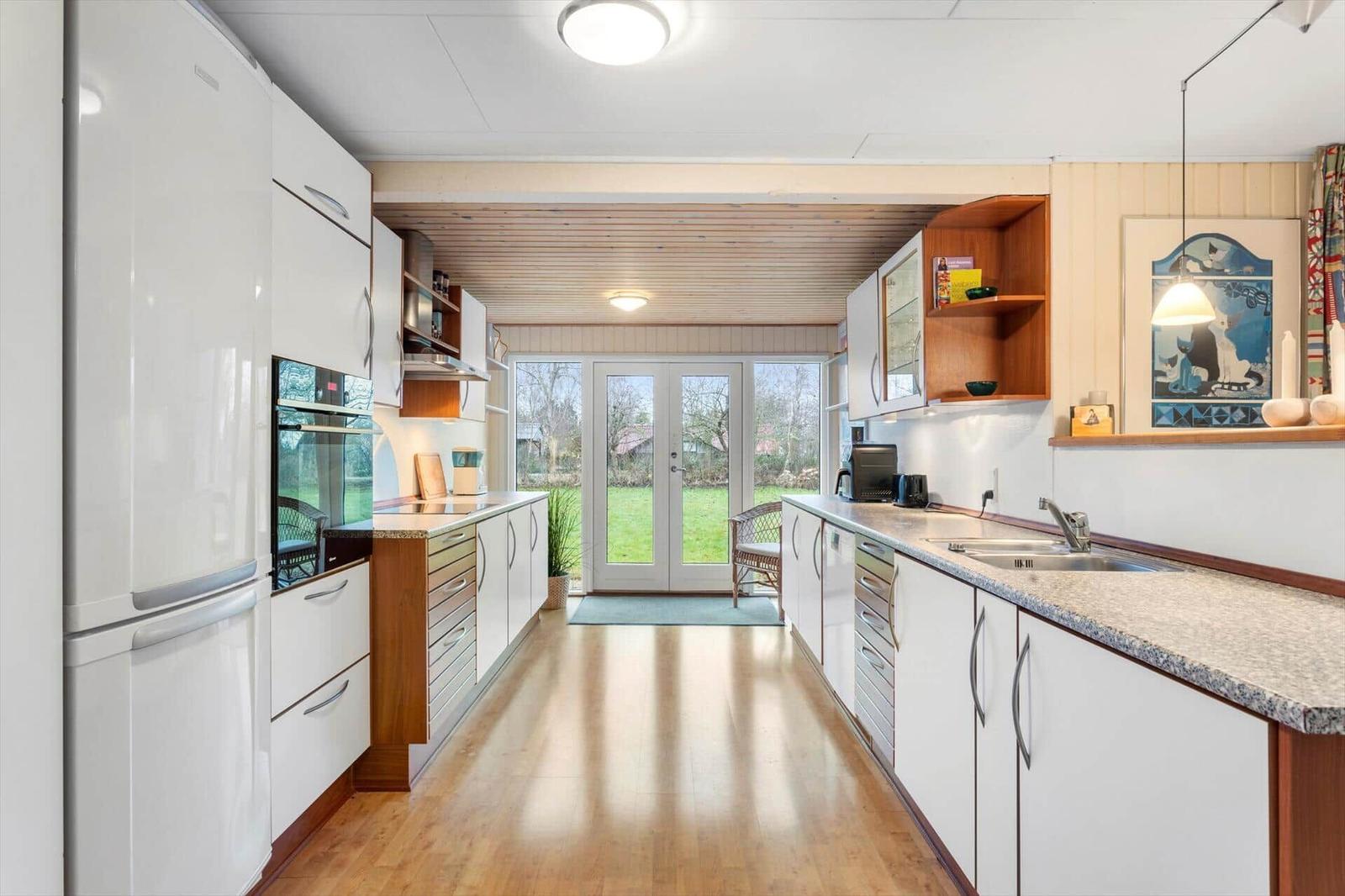 Kitchen with white cabinets, granite countertop, and view of the garden.
