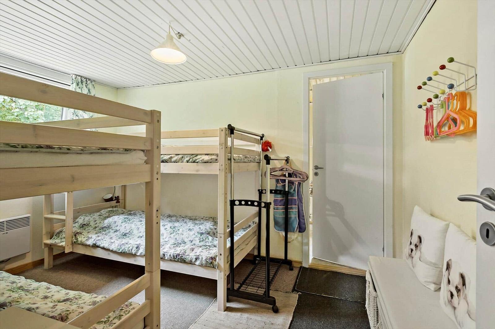Room with two bunk beds, clothes rack, and door to the bathroom.