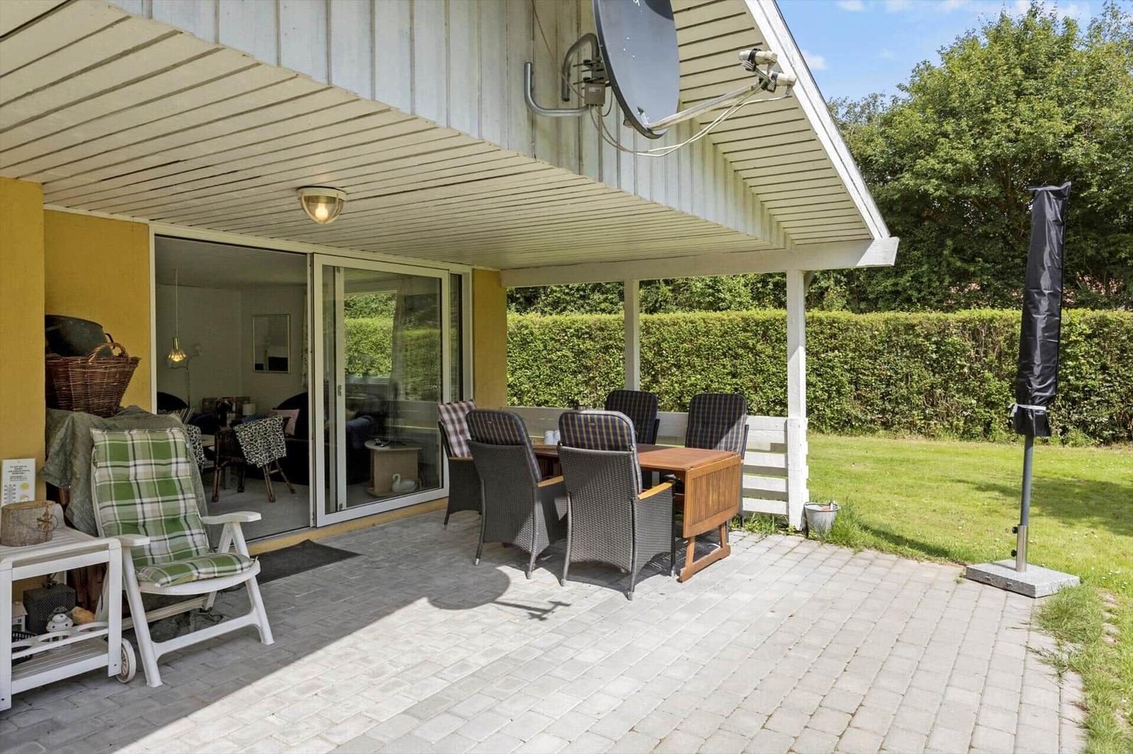 Terrace with table, chairs, and view of the garden. Sliding glass doors lead to the interior.