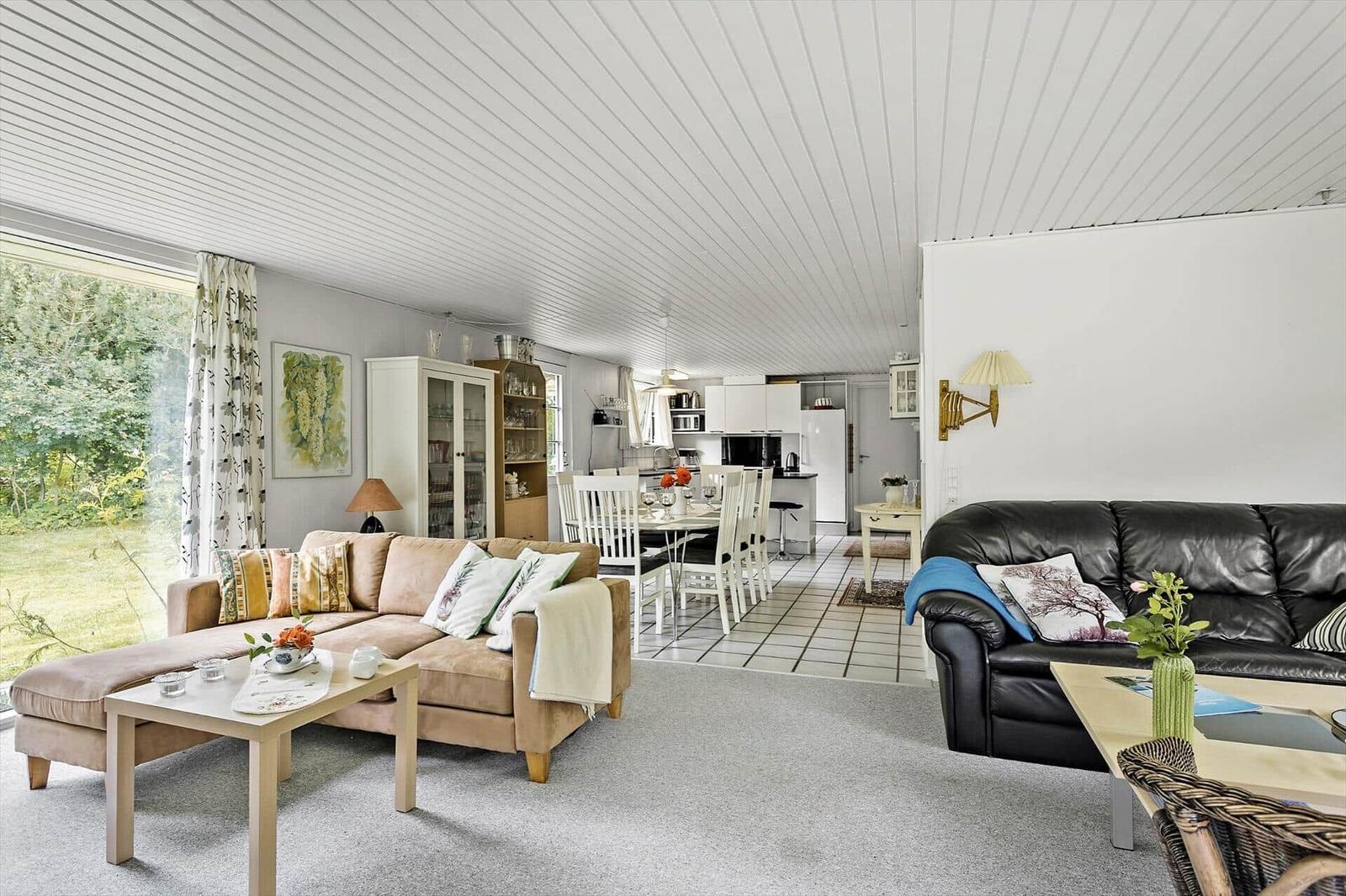 Living and dining area with sofa, dining table, and kitchen in background.