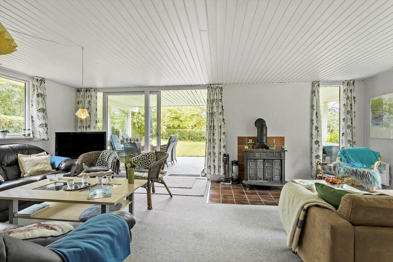 Living room with fireplace, sofa, table, and view of the garden.