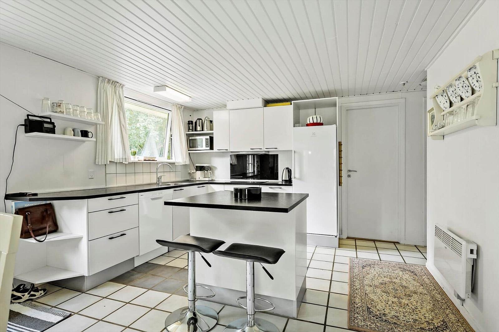 Kitchen with white cabinets, black countertops, and bar stools.