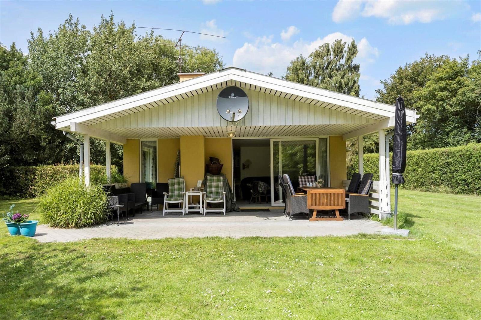 A house with terrace, garden, and satellite dish. Furniture and plants are visible.