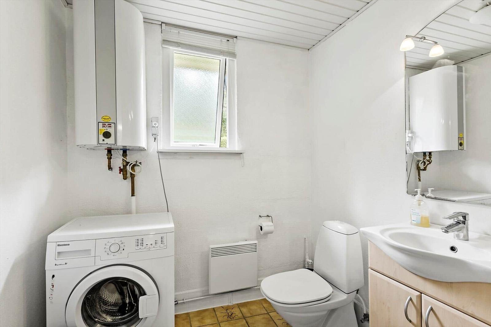 Bathroom with washing machine, toilet, and sink.