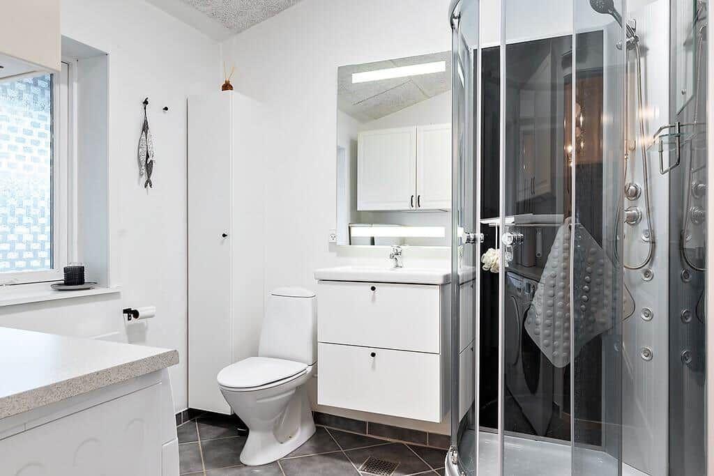 Bathroom with shower, sink and toilet. Window and mirror visible.