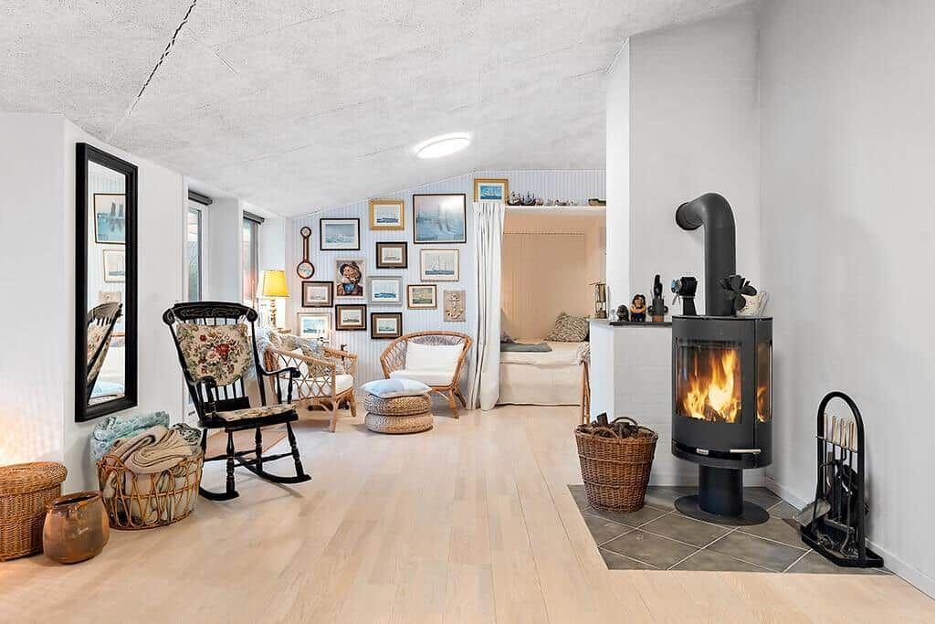 Living room with fireplace, chairs, and wall decor. Passage to bedroom.