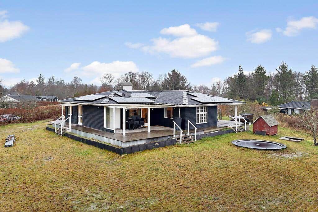 A dark-painted house with a terrace and an outdoor pool.