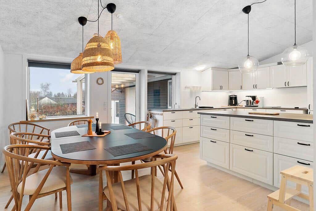 Kitchen with dining area, white cabinets, and wooden chairs around round table