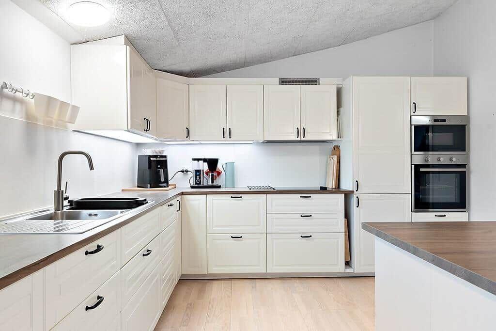 Modern kitchen with white cabinets, stainless steel appliances, and wood surfaces.