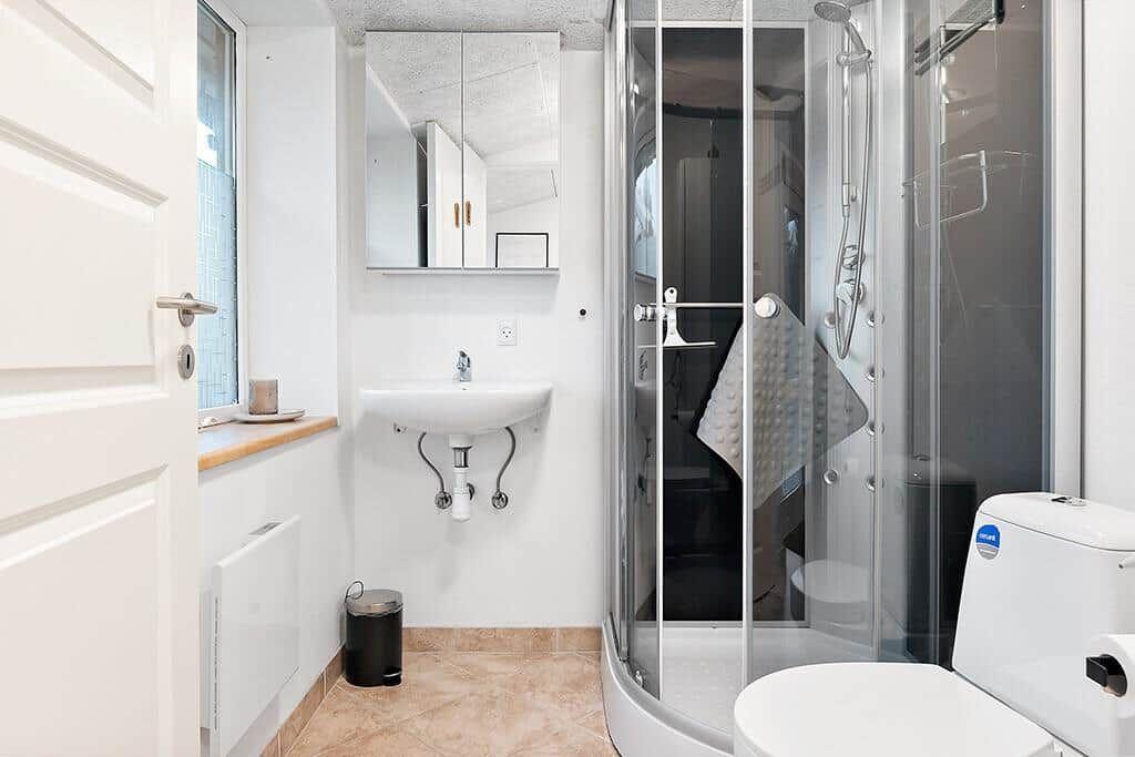 Bathroom with shower, sink, and toilet. Window and mirror visible.
