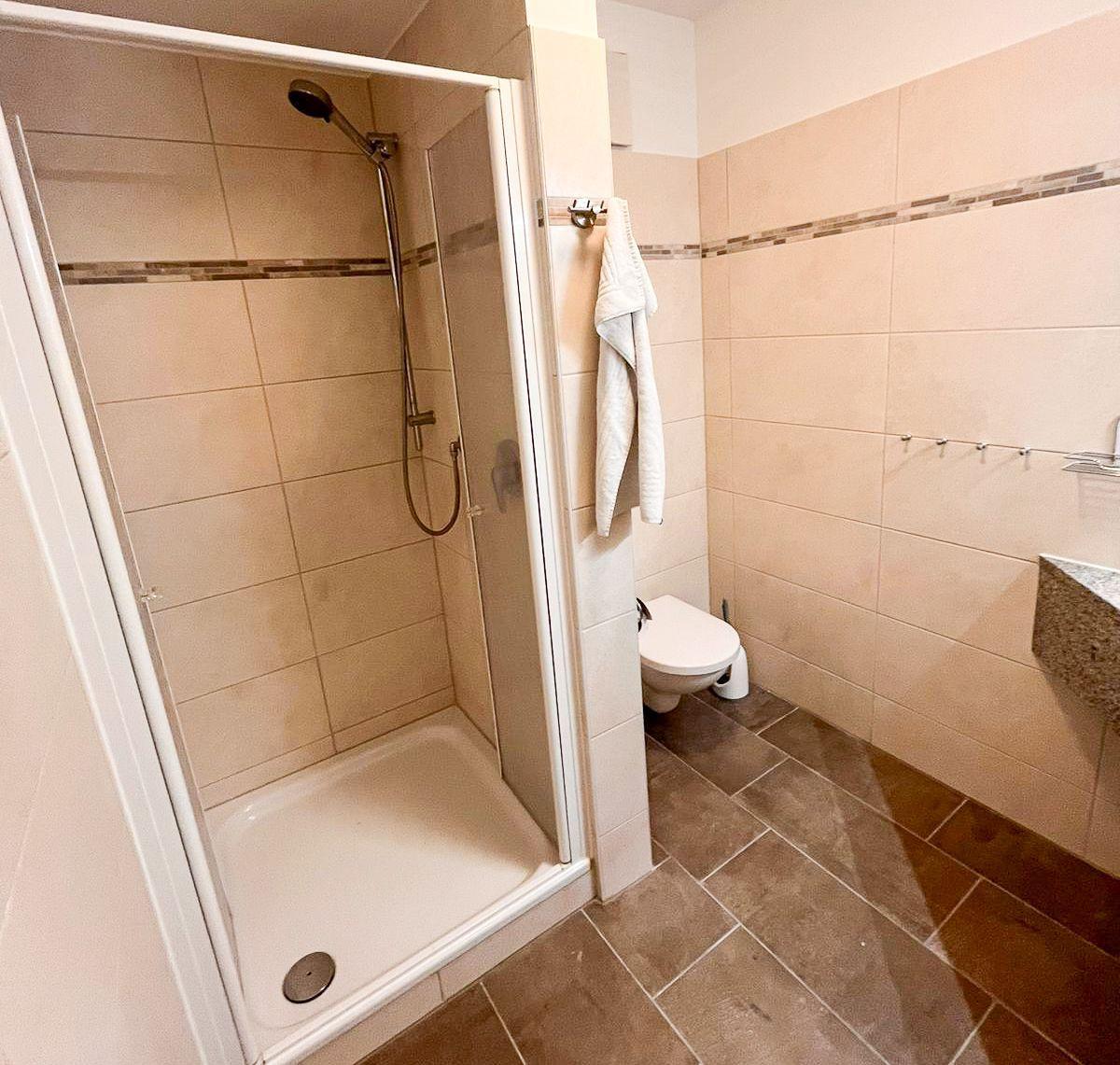 Badezimmer mit Dusche, Toilette und Waschbecken.