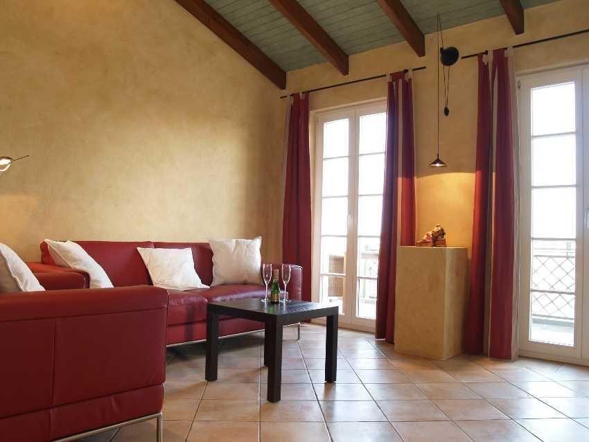 Ein Wohnzimmer mit rotem Sofa, Tisch und Fenstern mit roten Vorhängen.
