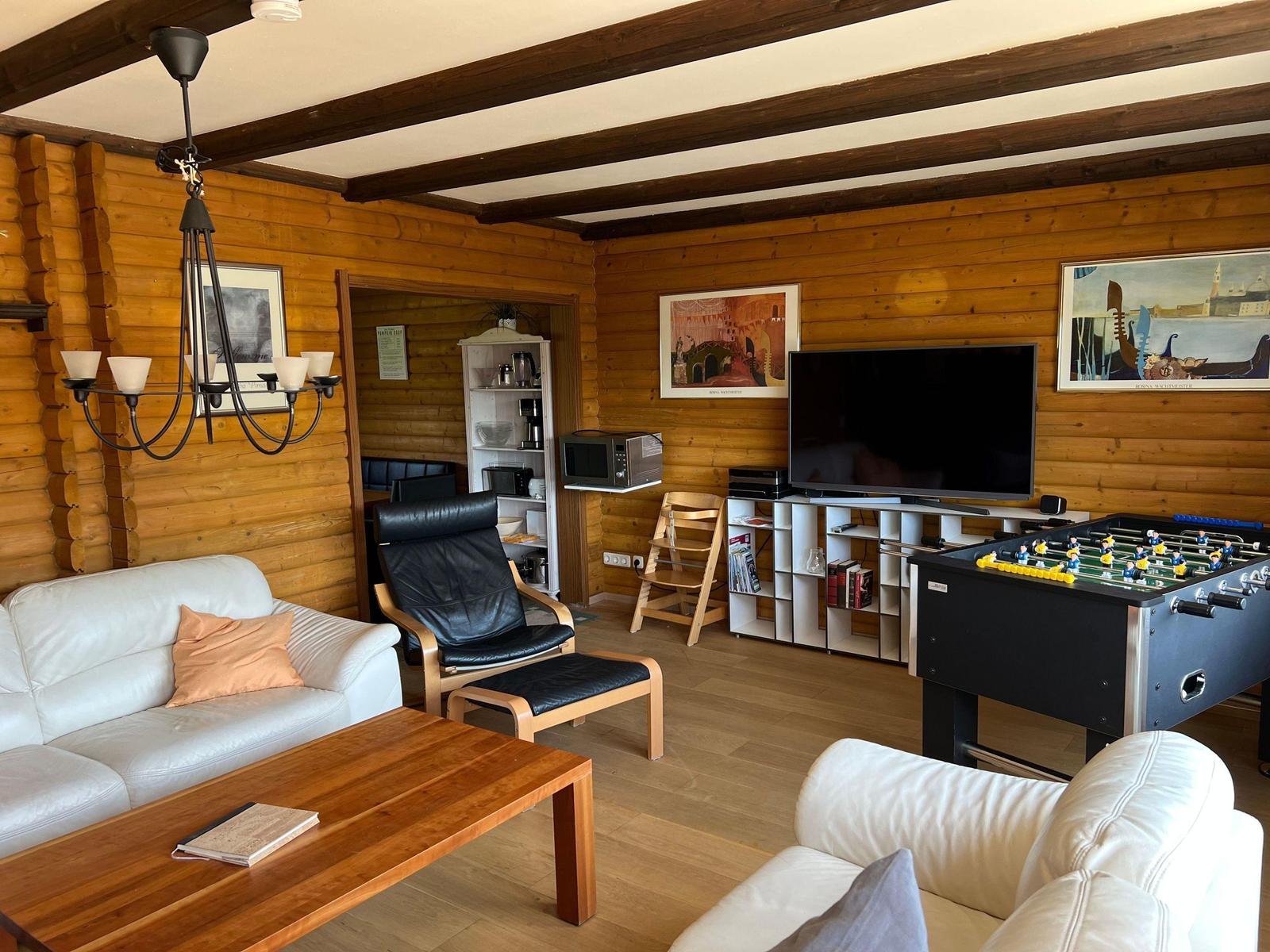 Living room with sofa, chair, table, TV, and foosball table.