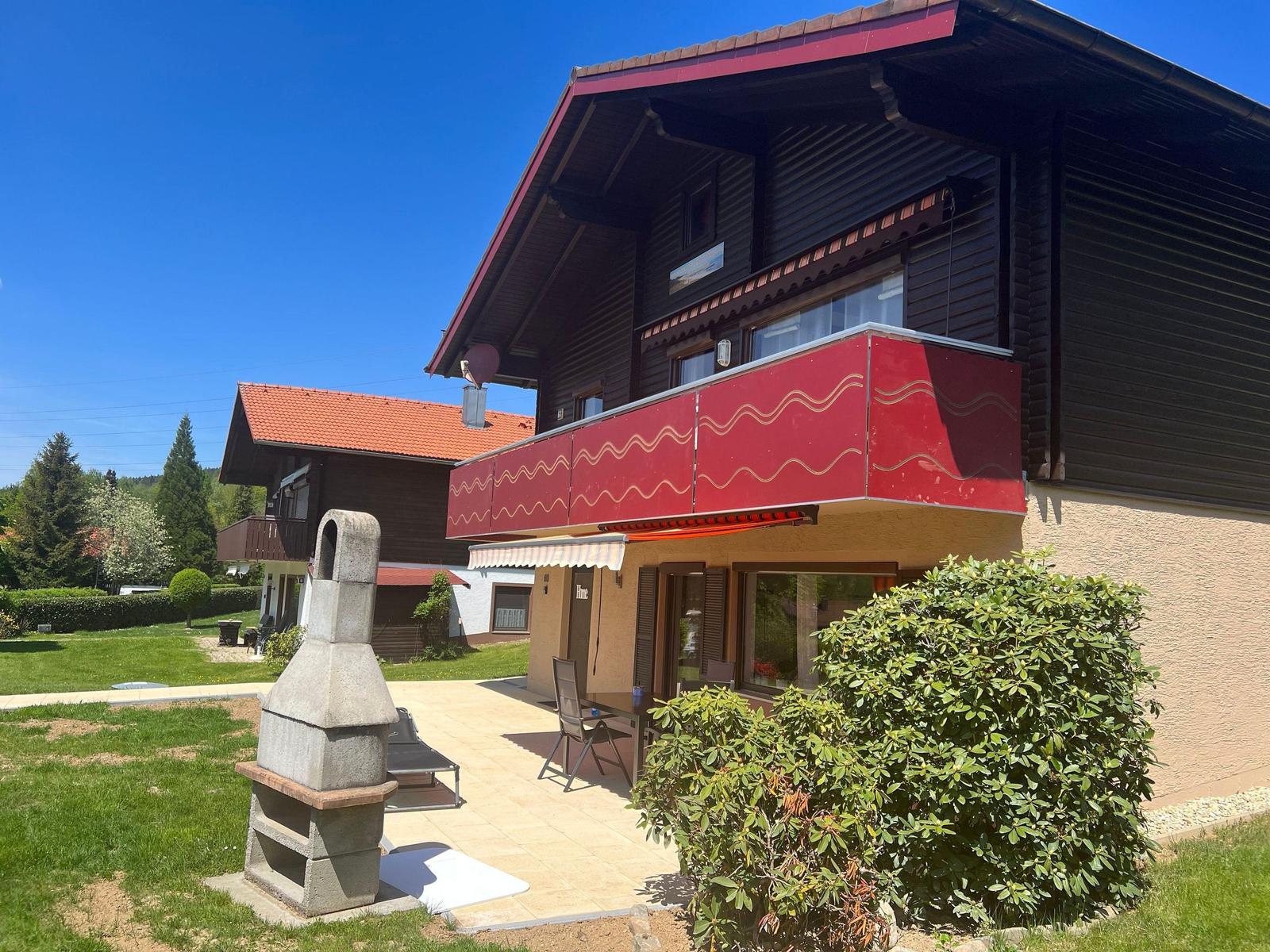 A two-story house with a balcony and terrace in the garden. A stone oven stands on the terrace.