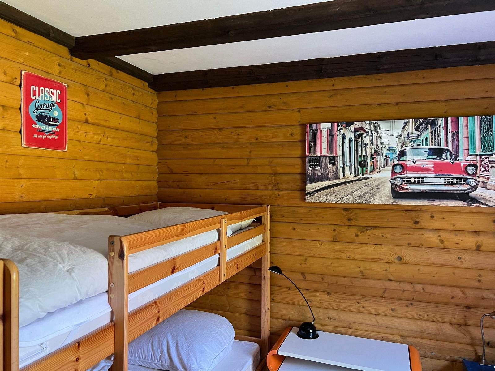 Room with bunk bed, wooden walls, and wall picture of a red car.