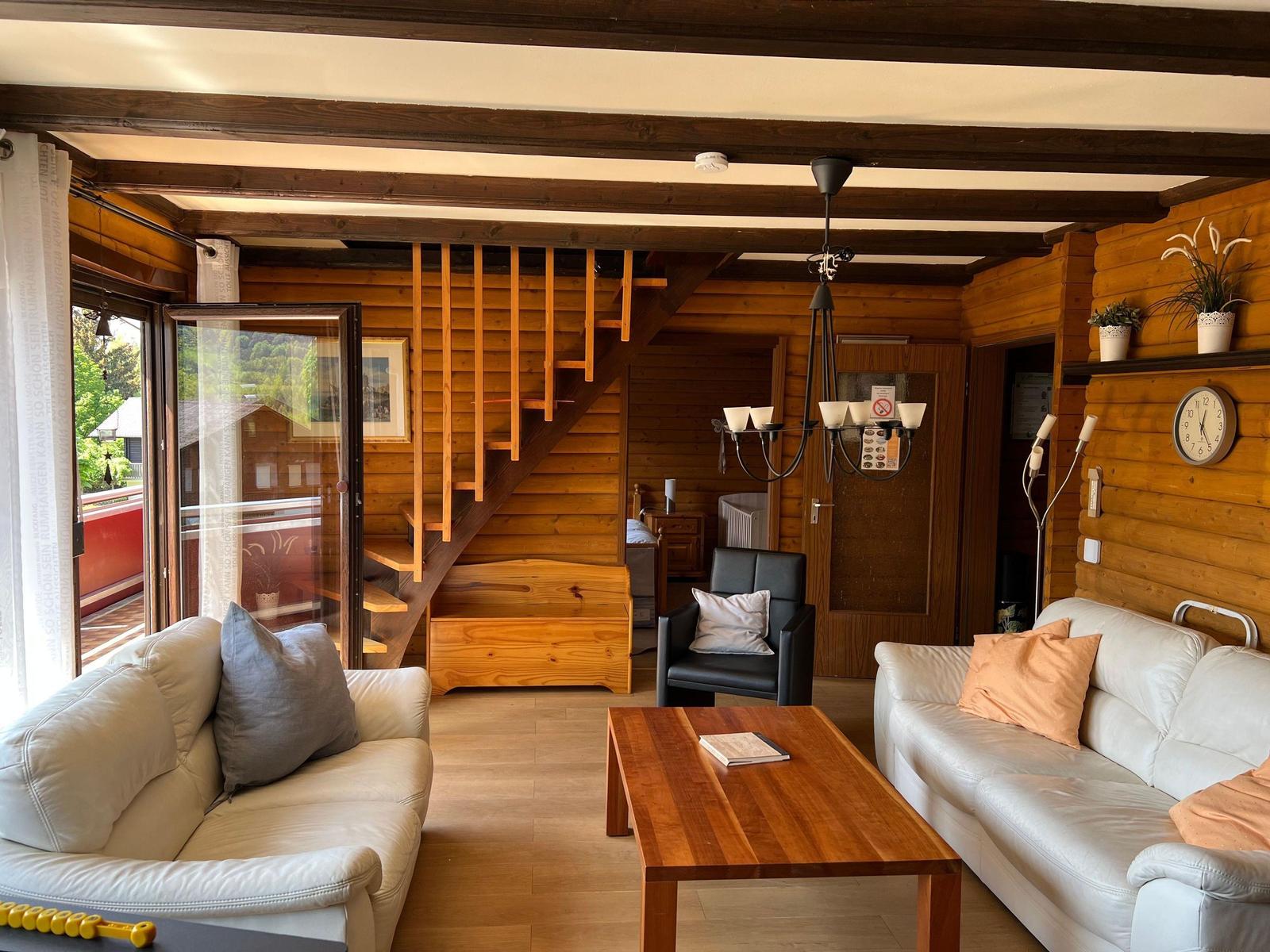 Living room with two sofas, table, and wooden stairs to upper level.