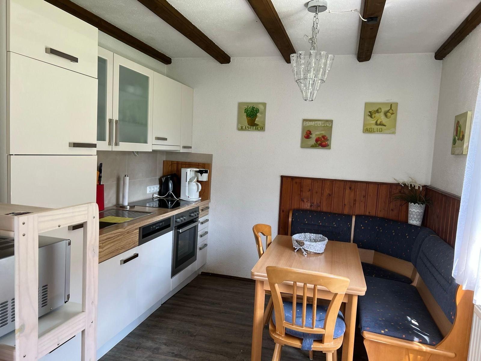 Kitchen with dining area, wooden beams, white cabinets, and kitchen counter.