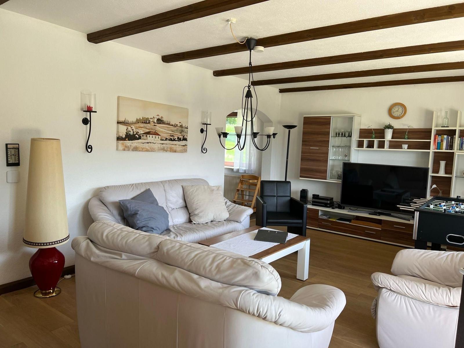 Living room with sofa, TV, and foosball table. Wooden beams on ceiling.