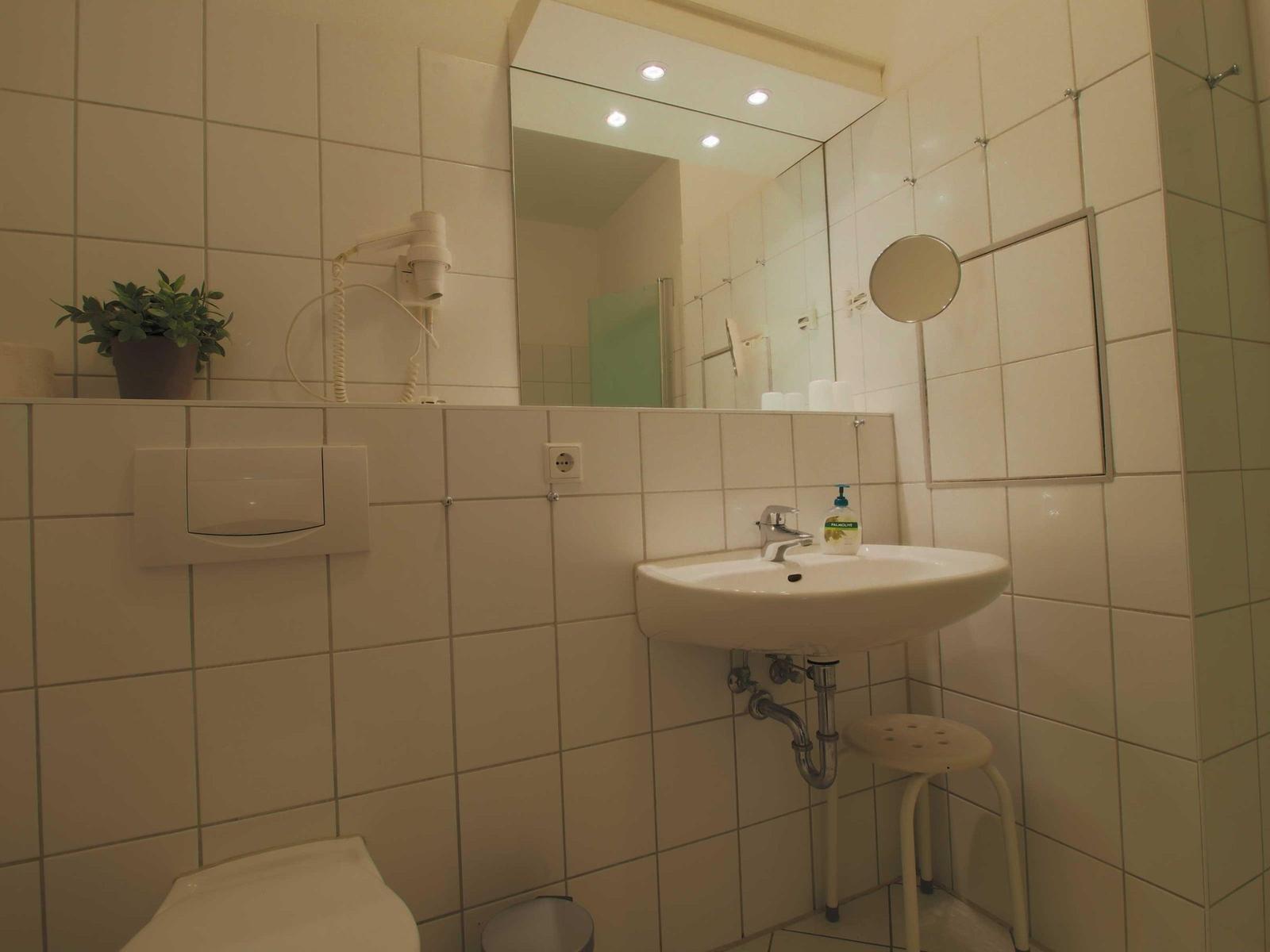 Badezimmer mit Waschbecken, Spiegel, Toilette und Handtuchhalter.