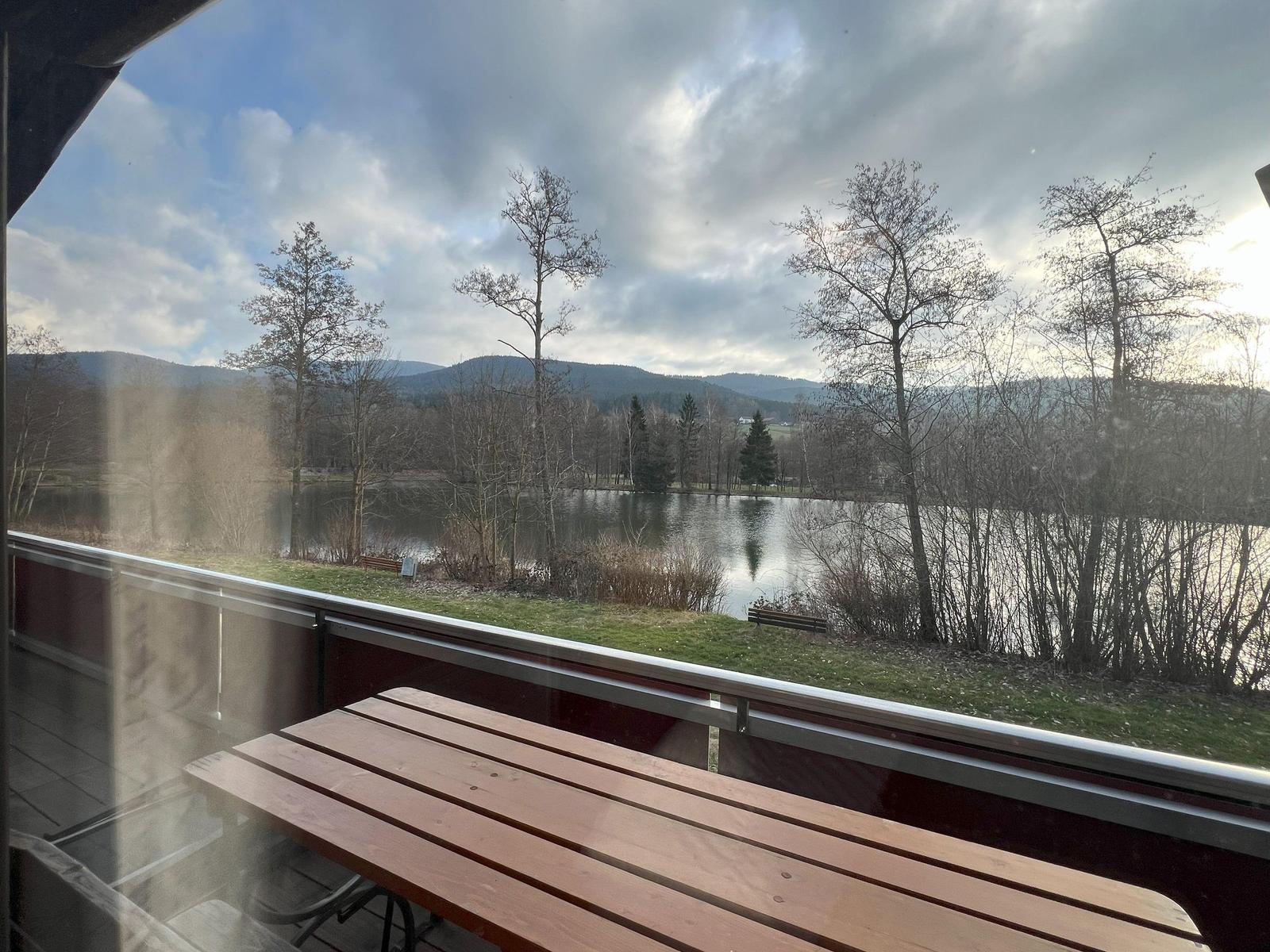 Terrace with table offers view of lake and hills.