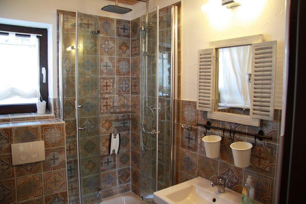 Bathroom with shower, sink, and window. Tiles with pattern.